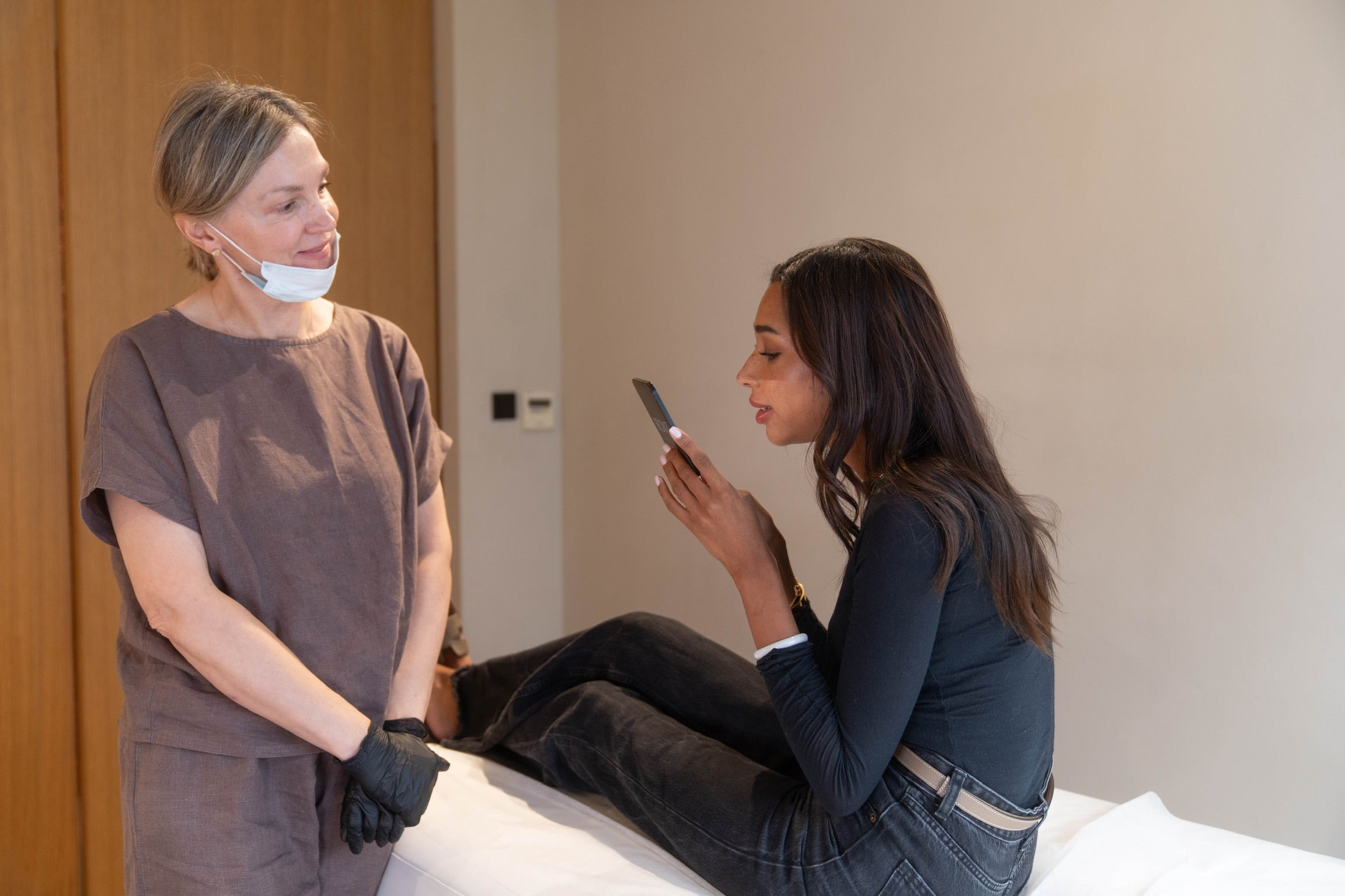 Practitioner smiling at client holding mirror after treatment session