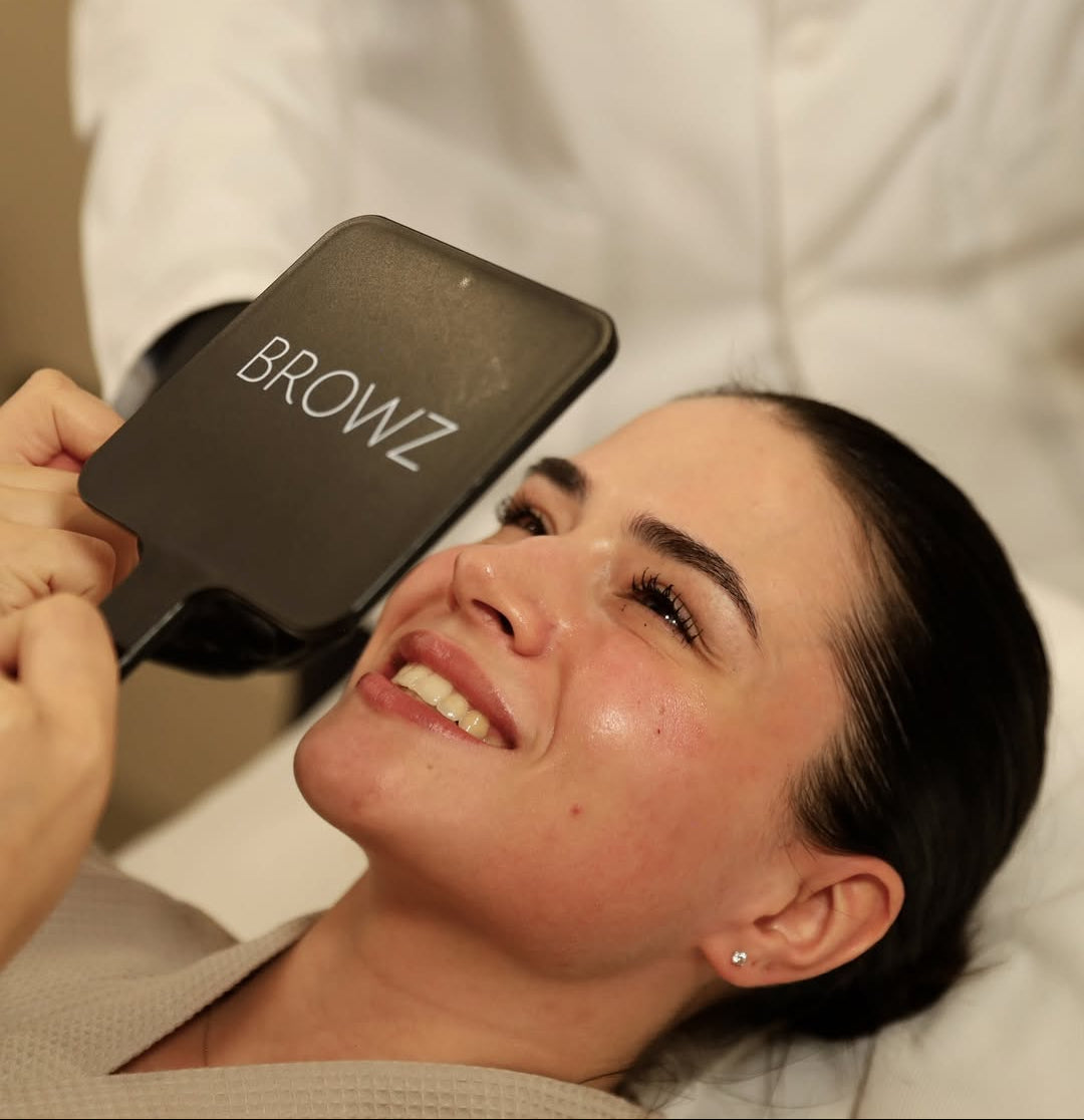 Happy client looking at the mirror with smooth, close-up skin texture after a Profhilo Dubai, showing hydration and tone at BROWZ.