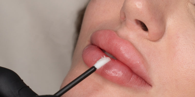 A woman comfortably receiving a lip blush aftercare in a clean, professional clinic setting