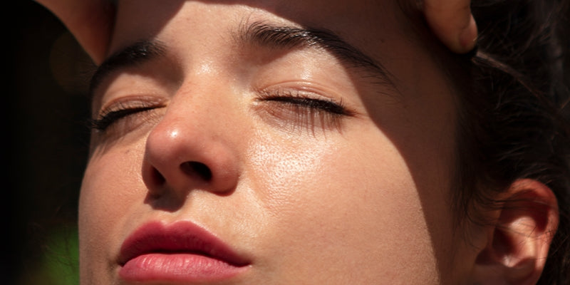 Woman slightly squinting under direct sunlight, with natural light hitting her face.