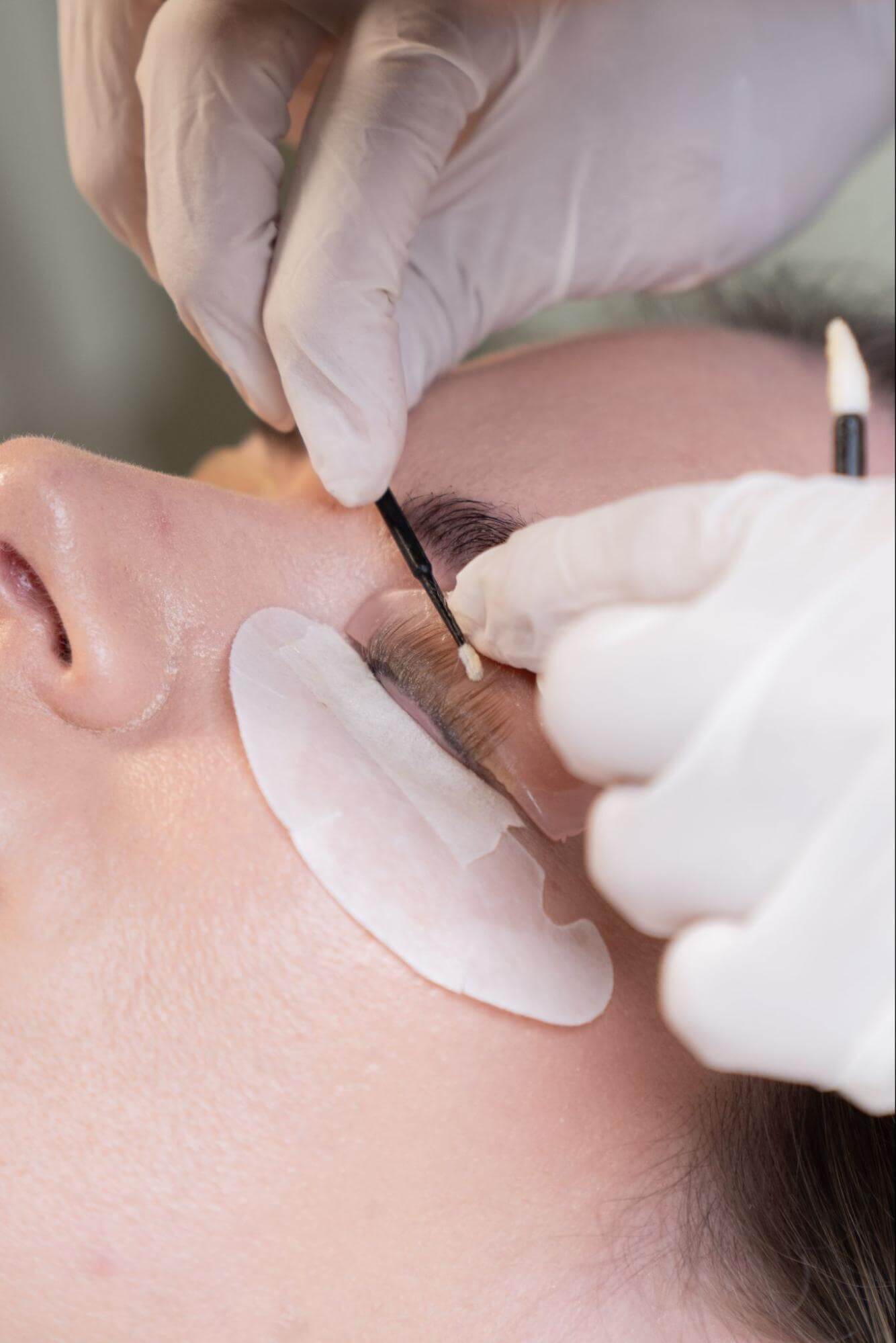 Korean lash lift, with a close look at a woman’s lashes during the session, showing precise professional application technique.