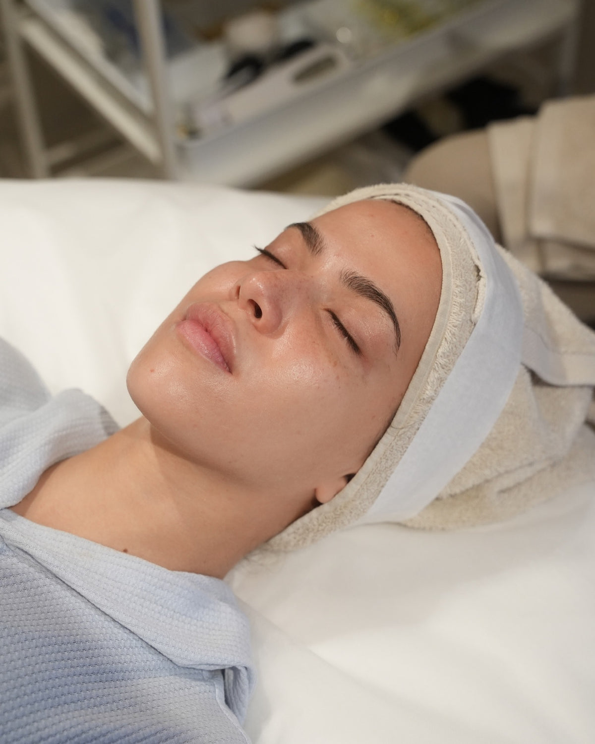 Client lying down with a headband during the preparation stage of a chemical peel treatment. 