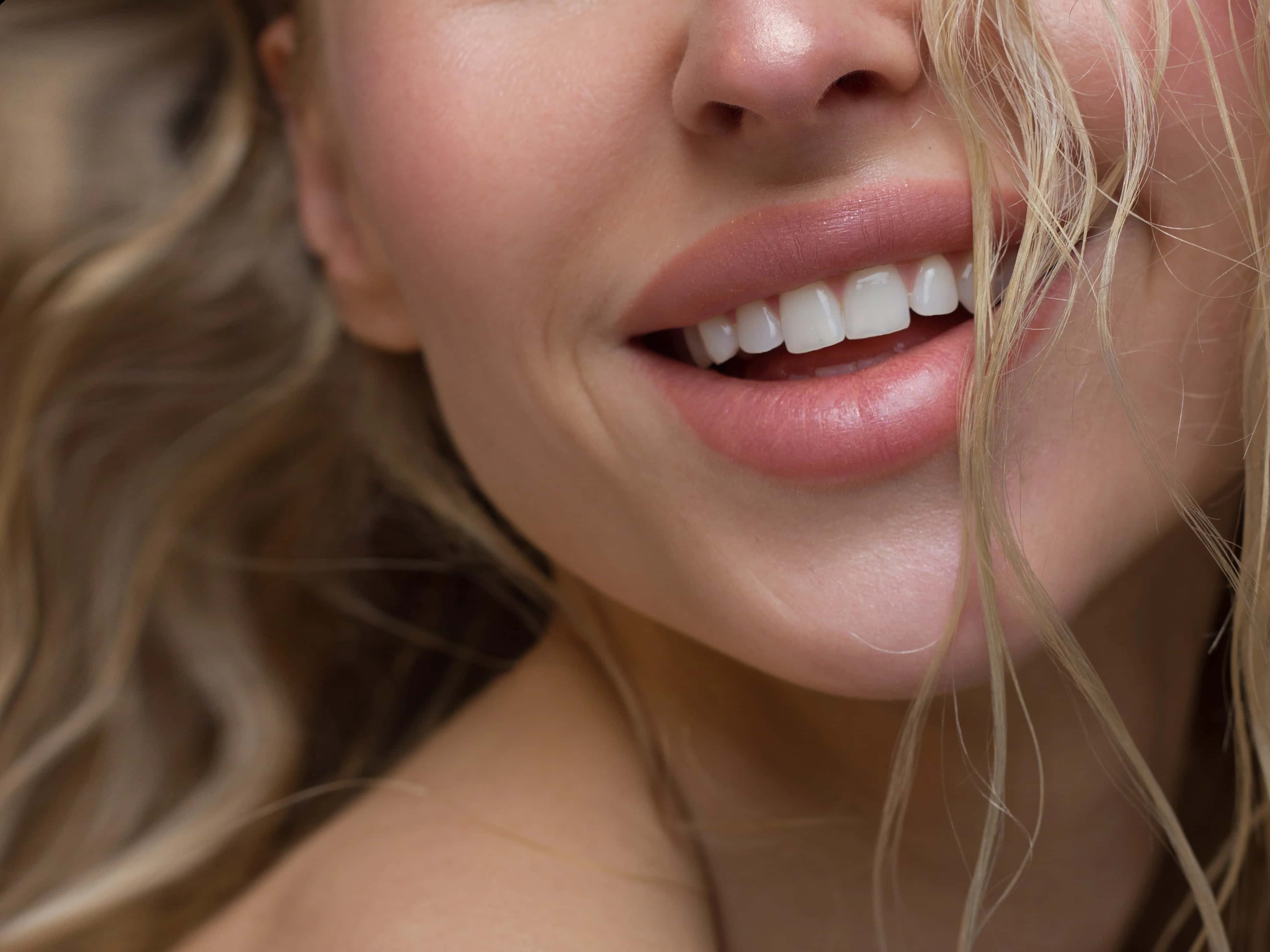 Close-up of a woman's radiant smile, representing the glow achieved after Profhilo treatment done by experts at BROWZ in Dubai.